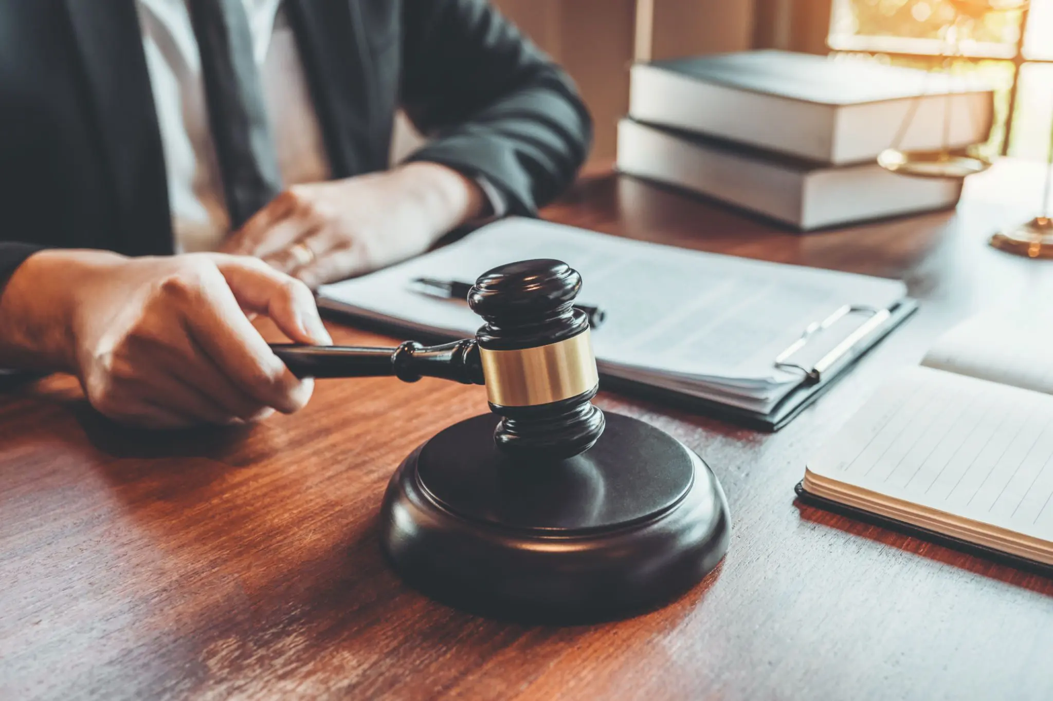 Judge holding gavel beside legal documents.